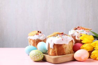Lezzetli Paskalya pastaları, laleler ve pembe ahşap masaya boyanmış yumurtalar arka planda, yakın plan. Metin için boşluk