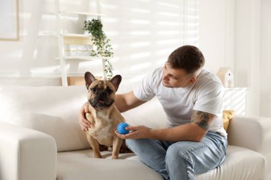 Evdeki kanepede dinlenen sevimli köpeğiyle genç bir adam.