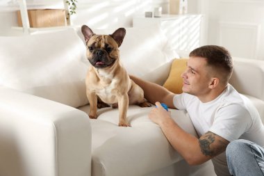 Evdeki kanepenin yanında tatlı köpeği ve oyuncağıyla rahatlayan genç bir adam.