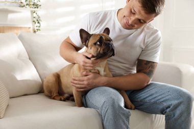 Evdeki kanepede dinlenen sevimli köpeğiyle genç bir adam.