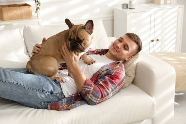 Evdeki kanepede dinlenen sevimli köpeğiyle genç bir adam.