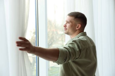 Evdeki güzel perdeleri açan adam.