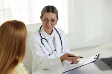 Klinikte gülümseyen kardiyologla randevusu olan bir kadın.