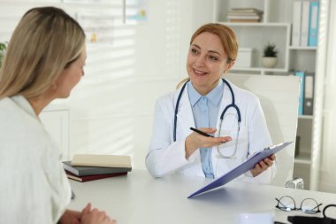 Klinikte gülümseyen kardiyologla randevusu olan bir kadın.