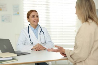 Klinikte gülümseyen kardiyologla randevusu olan bir kadın.