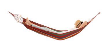 Şapkalı genç kadın beyaz arka planda hamakta dinleniyor.