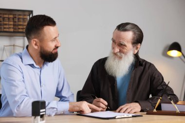 Noter, kıdemli adama ofisteki ahşap masada son arzusunu ve vasiyetnamesini imzalayacağı yeri gösteriyor.