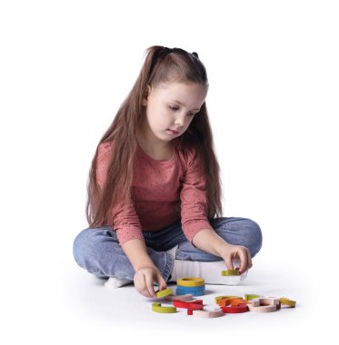 Beyaz arka planda renkli ahşap parçalarla oynayan sevimli küçük kız.