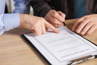 Noter, son vasiyet ve vasiyetnamenin nerede imzalanacağını gösteriyor. Ofisteki ahşap masada, yakın plan.