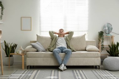 Evdeki kanepede dinlenen genç adam.