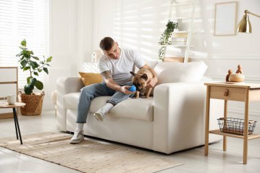 Evdeki kanepede dinlenen sevimli köpeğiyle genç bir adam.