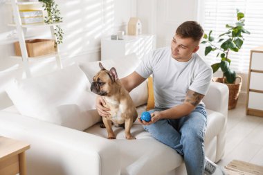 Evdeki kanepede dinlenen sevimli köpeğiyle genç bir adam.