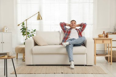 Evdeki kanepede dinlenen genç adam.