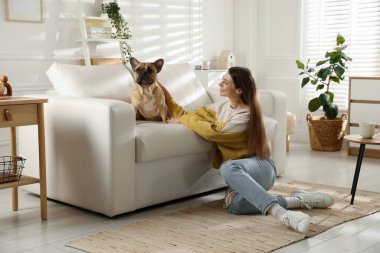 Evdeki kanepenin yanında tatlı köpeği olan bir kadın.
