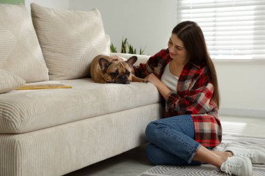 Evdeki kanepenin yanında sevimli köpeği olan bir kadın.