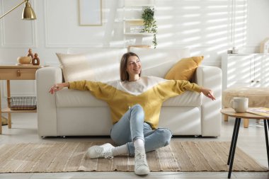 Evdeki koltuğun yanında dinlenen bir kadın.