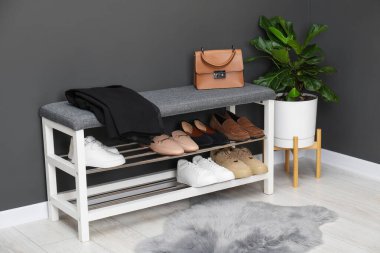 Gri duvarın yanında farklı ayakkabı, çanta ve çiçek depoları var.