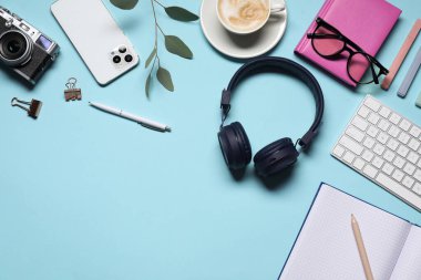 Kulaklıklar, bilgisayar klavyesi, akıllı telefon, klasik kamera, açık mavi arka planda kahve ve kırtasiye malzemesi, düz yatak. Metin için boşluk