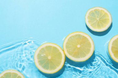 Açık mavi arka planda limon dilimleri, düz. Metin için boşluk
