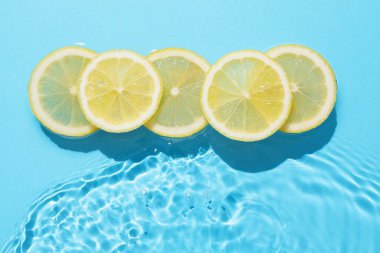Açık mavi zemin üzerinde limon dilimleri, düz uzanmış.