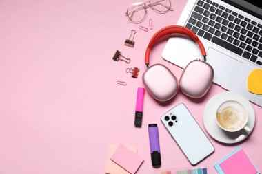 Kulaklık, akıllı telefon, dizüstü bilgisayar, kahve, pembe arka planda bardak ve kırtasiye malzemesi, düz yatak. Metin için boşluk