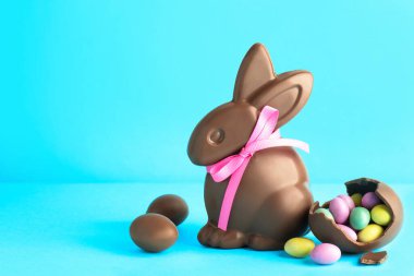 Çikolatalı Paskalya tavşanı ve açık mavi arka planda şekerli yumurta. Metin için boşluk