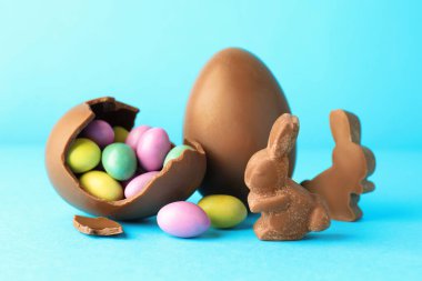 Çikolatalı Paskalya tavşanları ve açık mavi arka planda şekerli yumurtalar.