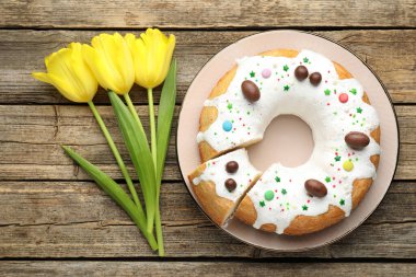 Lezzetli Paskalya pastası ve ahşap masada sarı laleler.
