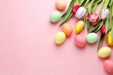 Boyalı Paskalya yumurtaları ve pembe arka planda güzel laleler. Metin için boşluk