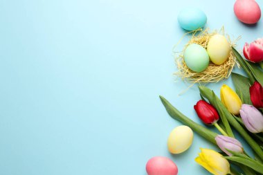 Boyanmış Paskalya yumurtaları ve açık mavi arka planda güzel laleler. Metin için boşluk