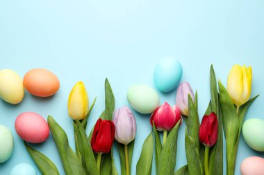 Boyanmış Paskalya yumurtaları ve açık mavi arka planda güzel laleler. Metin için boşluk