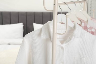 Yatağın yanındaki askıda asılı şık pijama gömlekler, yakın plan.