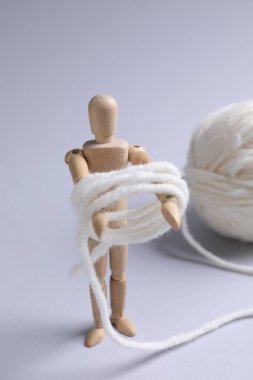 Hafif arka planda örgü ipliği olan ahşap manken, yakın plan.