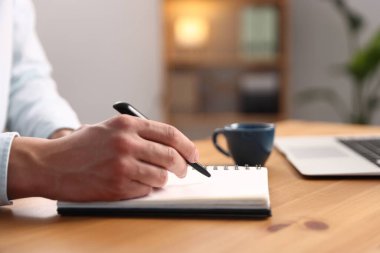 Ahşap masadaki kalemle deftere yazan adam, kapat