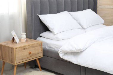 Yatak odasında temiz beyaz çarşafları olan rahat bir yatak.