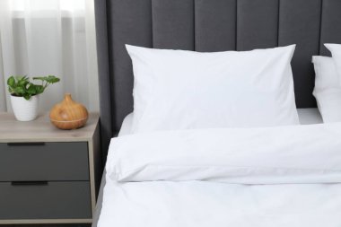 Yatak odasında temiz beyaz çarşafları olan rahat bir yatak.