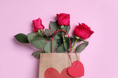 Pembe arka planda güller olan kağıt torba, üst manzara.