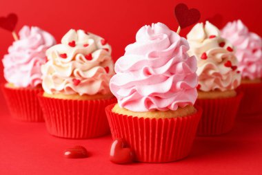 Sevgililer Günün kutlu olsun. Kırmızı arka planda kalpleri olan lezzetli kekler, yakın plan.