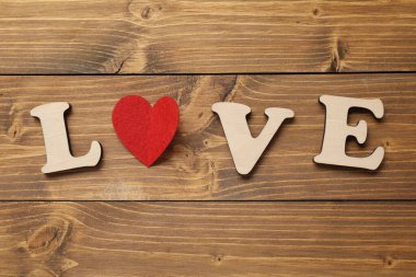 Sözcük Aşk harflerden ve kırmızı kalpten yapılmıştır ahşap masada, düz yatar