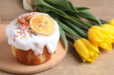 Lezzetli Paskalya pastası ve ahşap masada güzel laleler, yakın plan.