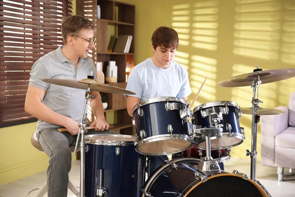 Genç çocuk içeride müzik öğretmeniyle bateri çalmayı öğreniyor.