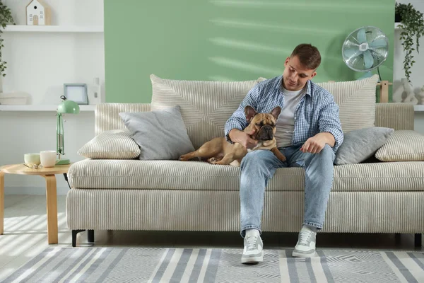 Evdeki kanepede dinlenen sevimli köpeğiyle genç bir adam.