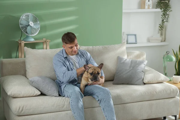 Evdeki kanepede dinlenen sevimli köpeğiyle genç bir adam.