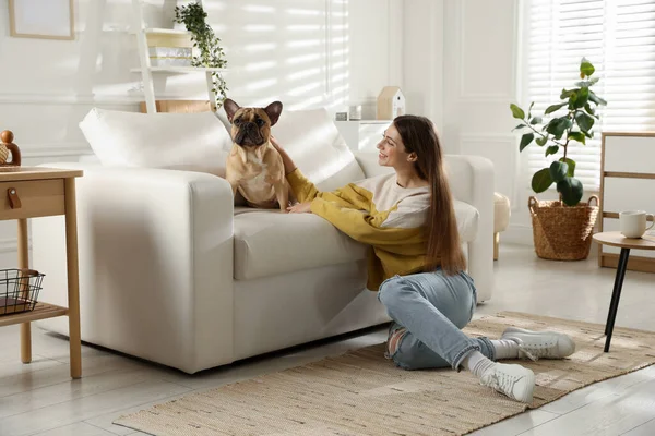 Evdeki kanepenin yanında tatlı köpeği olan bir kadın.
