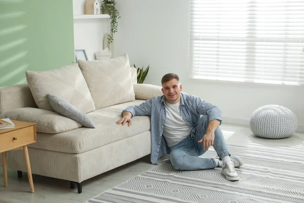 Evdeki kanepenin yanında dinlenen genç adam.