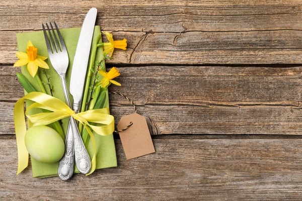 Paskalya sofrası. Güzel gümüş çatal bıçak dekoru ve ahşap arka planda boyanmış yumurta, üst manzara. Metin için boşluk