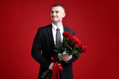 Sevgililer Günü kutlaması. Kırmızı arka planda güzel gül buketi olan adam.
