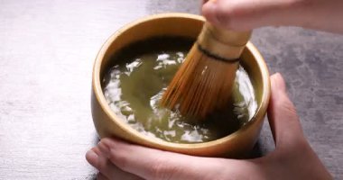 Gri masada yeşil kibriti bambu çırpıyla hazırlayan kadın, yakın plan.