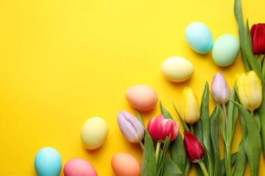 Boyalı Paskalya yumurtaları ve sarı arka planda güzel laleler. Metin için boşluk