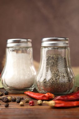 Ahşap masada baharatlı tuzluk ve biberlikler, yakın plan.